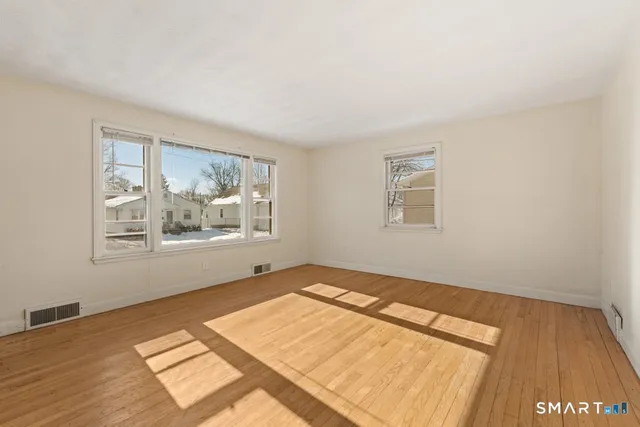 a view of a big room with wooden floor and windows