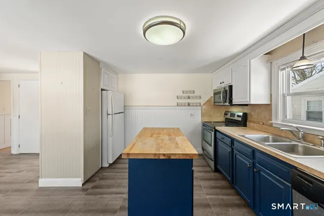 a kitchen with kitchen island granite countertop wooden cabinets a sink a stove and a refrigerator