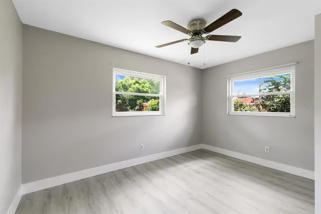 an empty room with wooden floor and ceiling fan