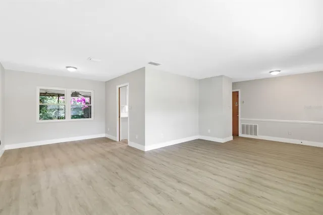 a view of an empty room with wooden floor and window