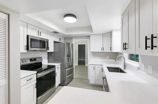 a kitchen with stainless steel appliances a stove a sink dishwasher a refrigerator and a microwave