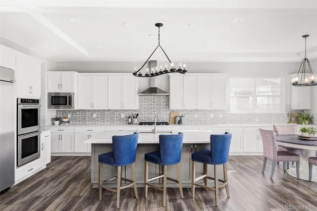 a kitchen with a dining table chairs stainless steel appliances and cabinets