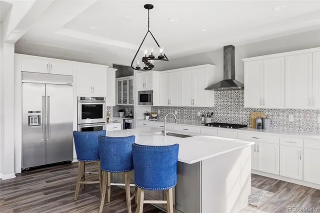 a kitchen with stainless steel appliances kitchen island granite countertop a sink a stove a refrigerator cabinets and chairs