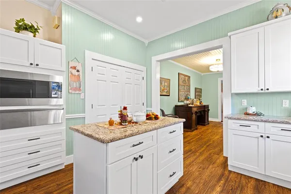 a kitchen that has a lot of cabinets in it and wooden floors