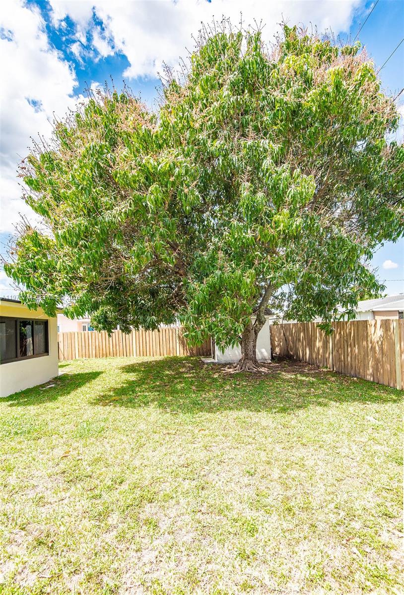 11861 Southwest 185th Terrace Miami, FL 33177 - Photo 9 of 34 a view of a yard with a house and large trees with wooden fence