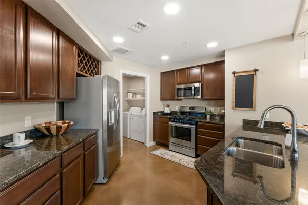 a kitchen with stainless steel appliances granite countertop a refrigerator a stove a sink a oven with a dining table and chairs