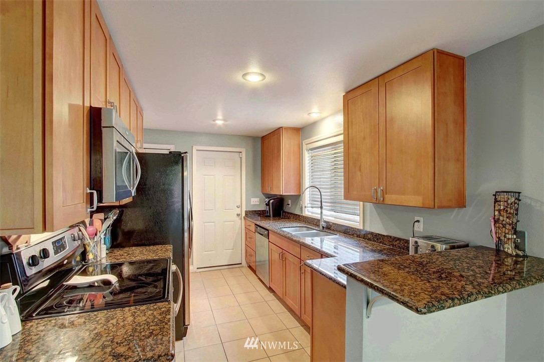 2227 Southeast 8th Place Renton, WA 98057 - Photo 7 of 21 a kitchen with stainless steel appliances granite countertop a sink stove and a refrigerator