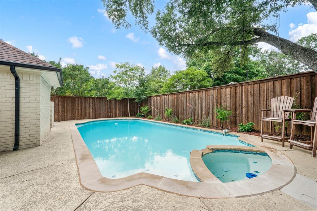 6403 Genstar Lane Dallas, TX 75252 - Photo 30 of 34 Private backyard featuring a swimming pool with an integrated spa, expansive concrete decking, and a perimeter privacy fence