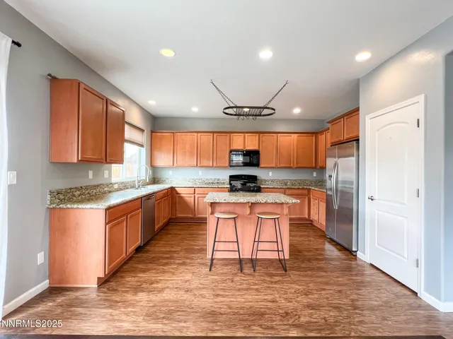 a kitchen with stainless steel appliances granite countertop a refrigerator a sink dishwasher a stove and white cabinets with wooden floor