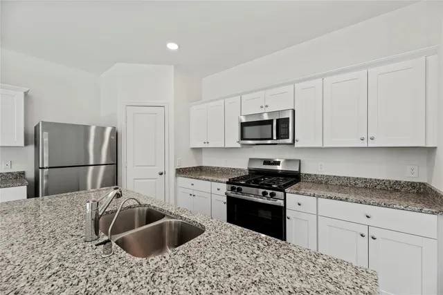 a kitchen with granite countertop a sink stove and refrigerator
