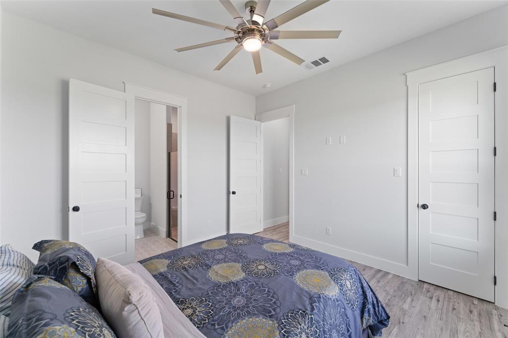 4411 Fm 751 Wills Point Wills Point, TX 75169 - Photo 28 of 40 Bedroom featuring an overhead ceiling fan with lighting, wood-finish flooring, white paneled doors with black hardware, and an adjacent bathroom with a toilet and shower enclosure