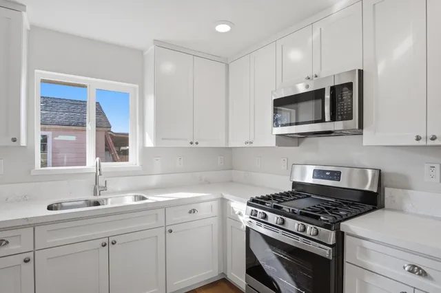a kitchen with cabinets stainless steel appliances a sink and a window