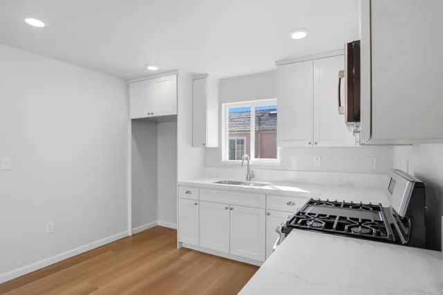 a kitchen with granite countertop a stove a sink and a refrigerator