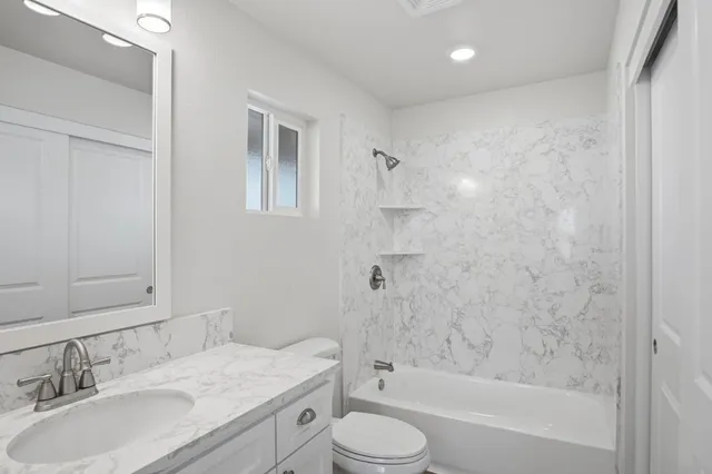 a bathroom with a granite countertop sink toilet and shower