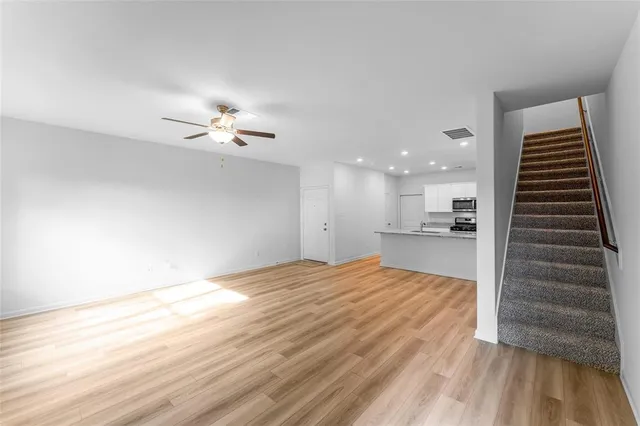 a view of kitchen and empty room with wooden floor