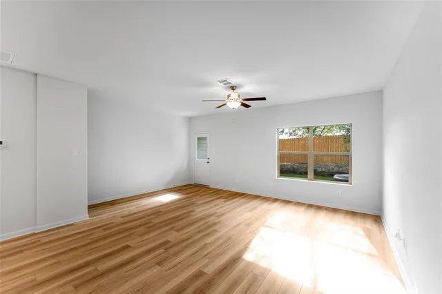 a view of an empty room with a window and wooden floor