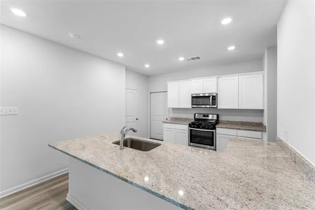 a kitchen with stainless steel appliances granite countertop a sink and stove top oven