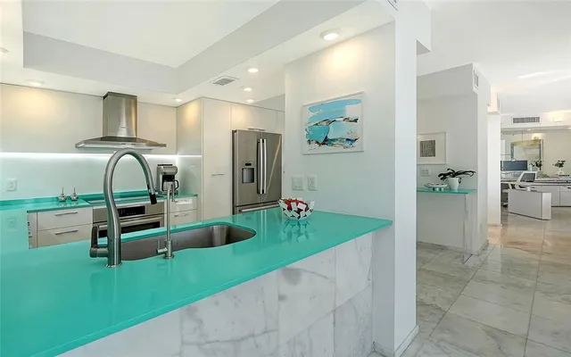 a kitchen with kitchen island granite countertop a refrigerator and a sink