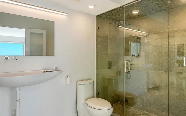 a bathroom with a shower sink mirror and toilet