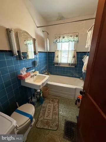 a bathroom with a sink a toilet a mirror and bathtub