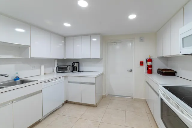 a kitchen with white cabinets and refrigerator