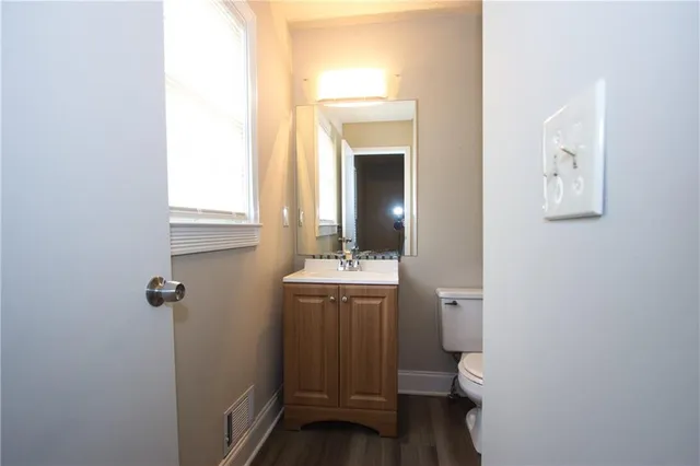 a bathroom with a granite countertop sink and a toilet