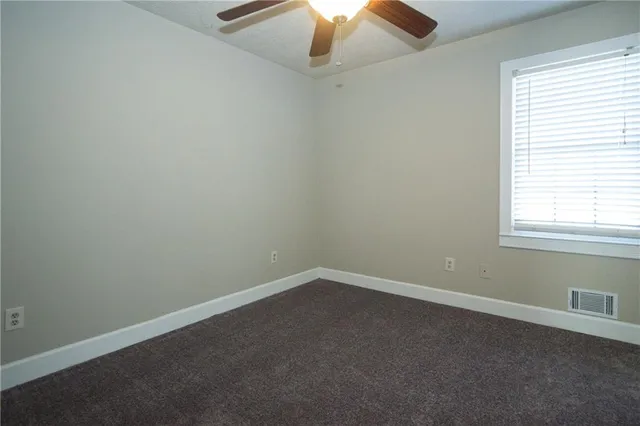 an empty room with a window and a fan