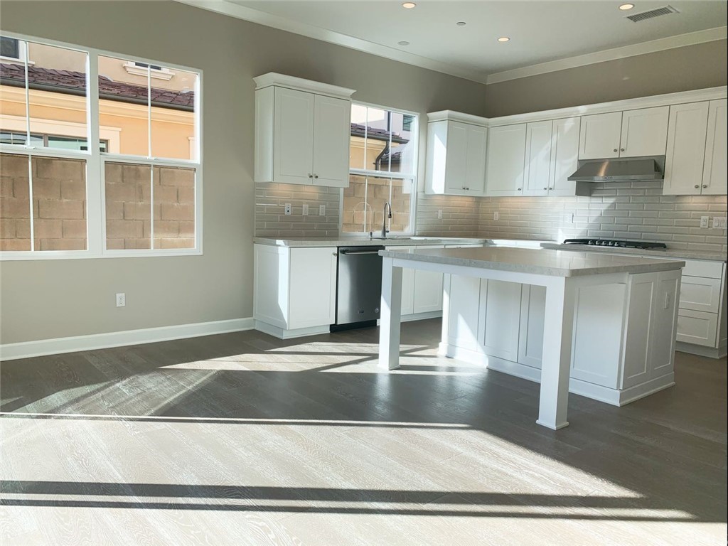 68 Singer Irvine, CA 92620 - Photo 3 of 12 a kitchen with stainless steel appliances granite countertop a sink stove and white cabinets with wooden floor