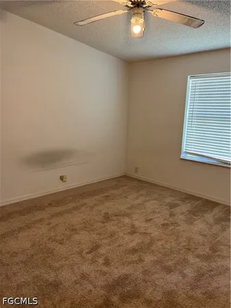 an empty room with a chandelier fan and windows