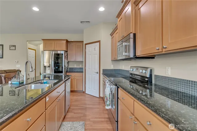 a kitchen with stainless steel appliances granite countertop a sink stove and refrigerator
