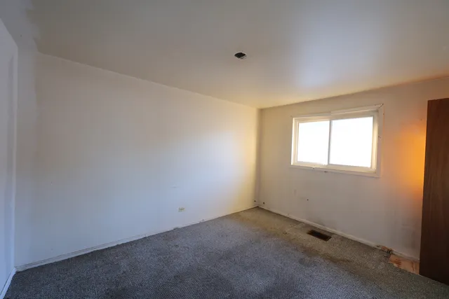 a view of an empty room with a fireplace and a window