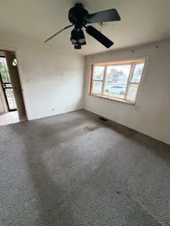 en empty room with windows and ceiling fan