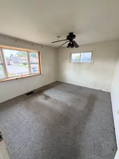 an empty room with windows and ceiling fan