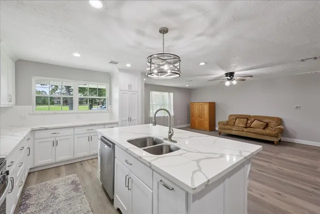 a kitchen with stainless steel appliances granite countertop a sink dishwasher and a stove with wooden floor