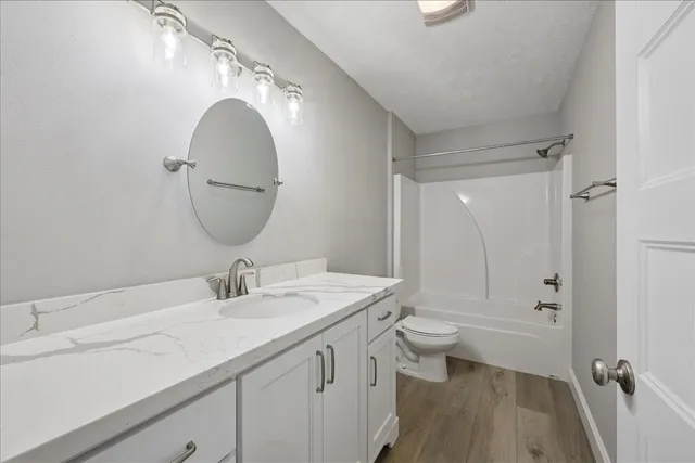 a bathroom with a sink a toilet a mirror and shower