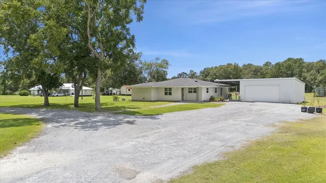 a white house with a big yard and large trees