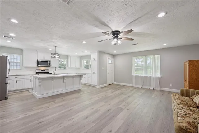 a view of kitchen with microwave a stove and white cabinets