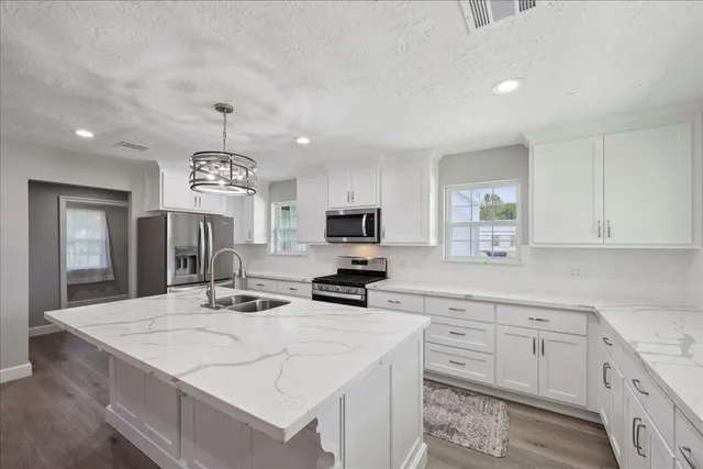 a kitchen with kitchen island granite countertop a sink a center island and cabinets
