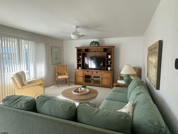 a living room with furniture a flat screen tv and a large window