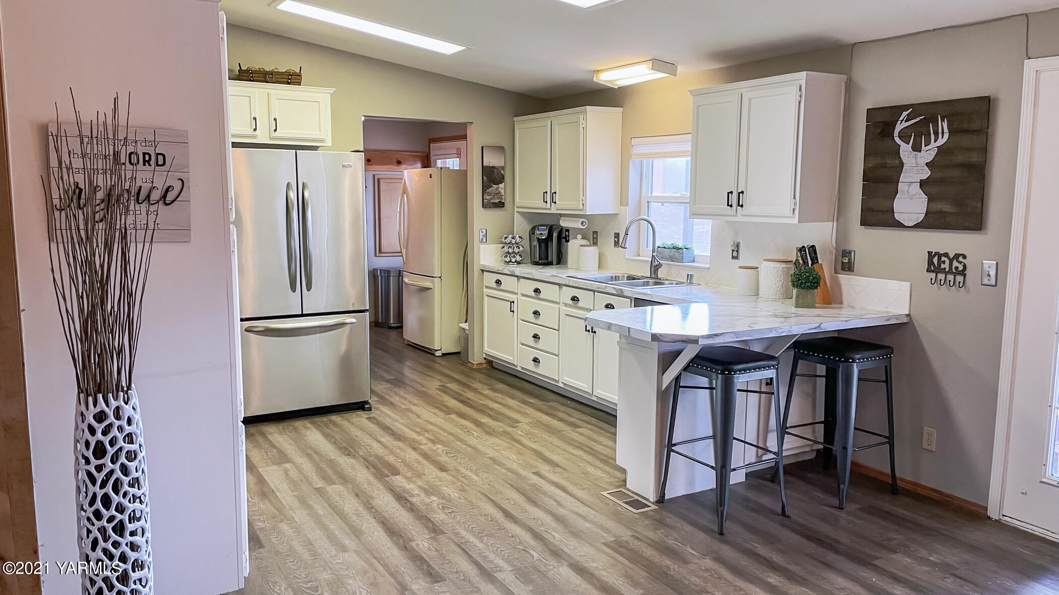 661 Wakatak Road Yakima, WA 98908 - Photo 4 of 20 a kitchen with stainless steel appliances granite countertop a refrigerator a sink dishwasher and white cabinets with wooden floor