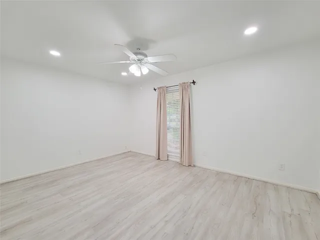 an empty room with wooden floor and ceiling fan