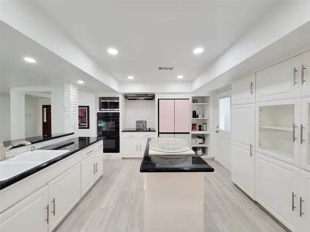 a large white kitchen with stainless steel appliances kitchen island a large counter top and a stove top oven
