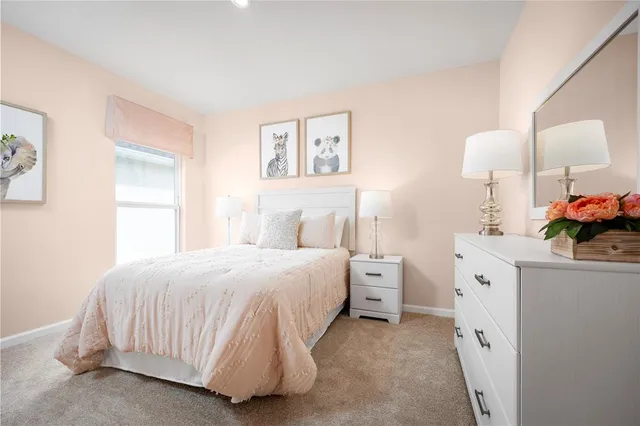 a spacious bedroom with a bed and a lamp on the dresser