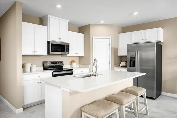 a kitchen with a refrigerator a stove a sink and chairs