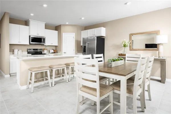 a kitchen with stainless steel appliances kitchen island granite countertop a table chairs microwave and white cabinets