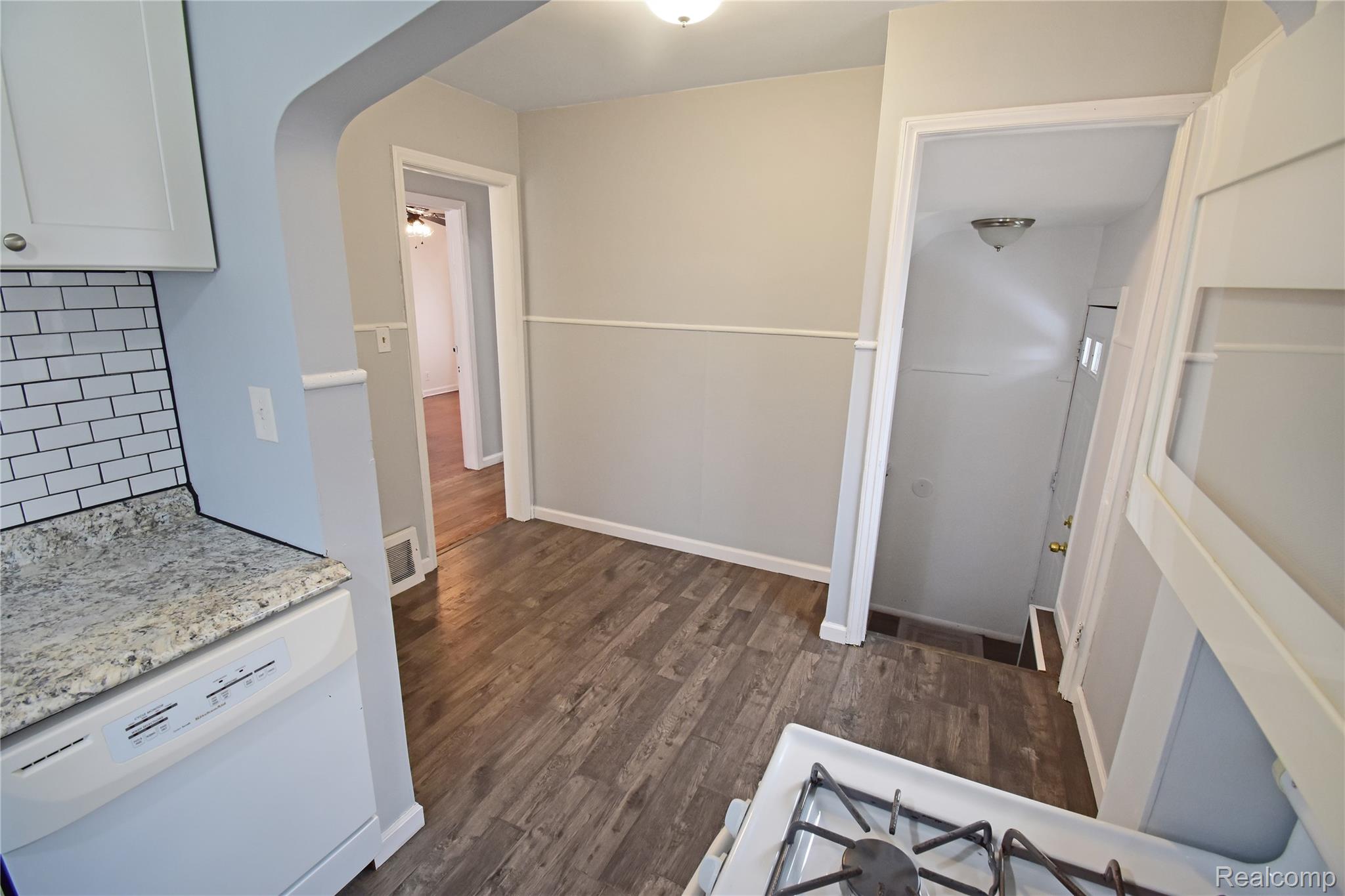8305 Stephens Road Center Line, MI 48015 - Photo 17 of 23 Kitchen with white appliances, white cabinets, dark wood-type flooring, arched walkways, and light stone countertops