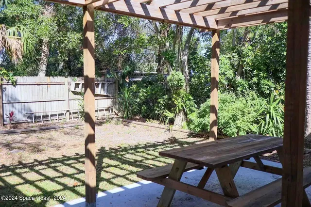 a view of a backyard with table and chairs with wooden fence and plants