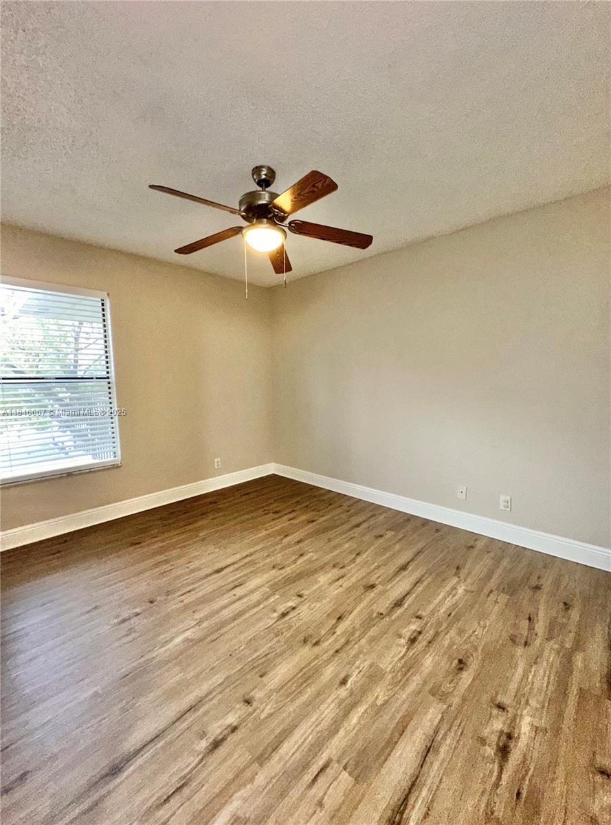 1620 Balfour Point Drive, Unit G West Palm Beach, FL 33411 - Photo 11 of 15 an empty room with wooden floor fan and windows