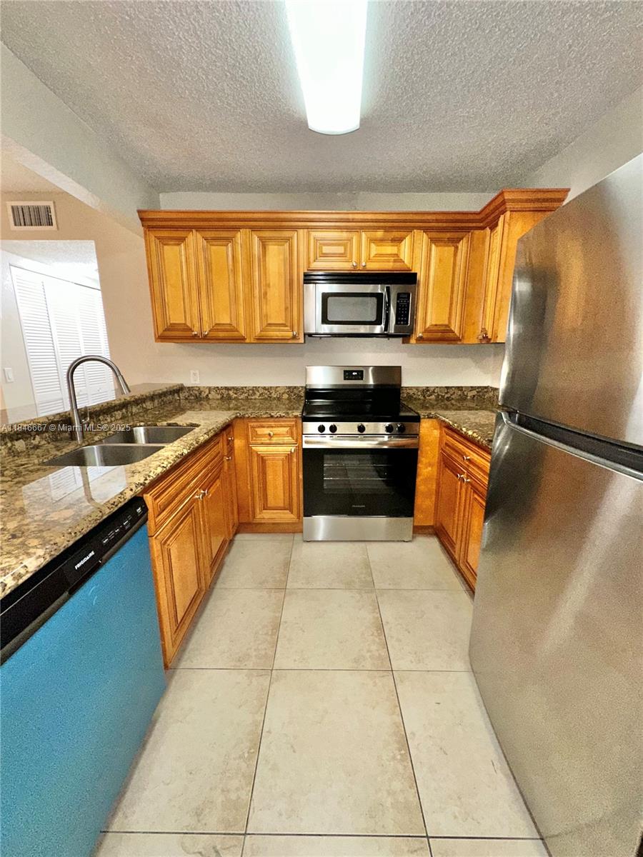 1620 Balfour Point Drive, Unit G West Palm Beach, FL 33411 - Photo 3 of 15 a kitchen with stainless steel appliances granite countertop a sink stove and refrigerator