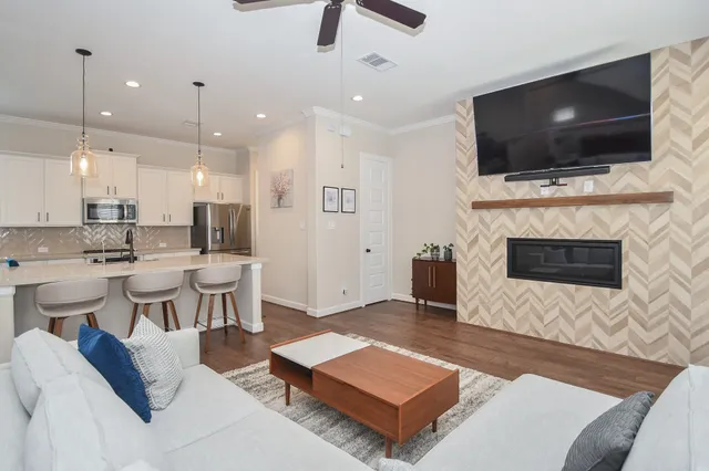 a kitchen with stainless steel appliances kitchen island granite countertop a dining table chairs refrigerator and wooden floor